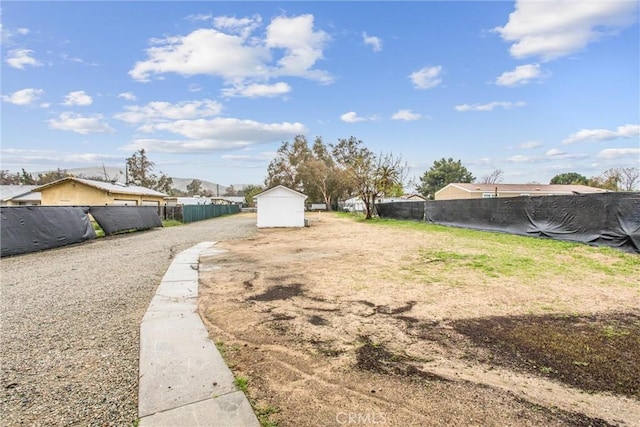 view of yard featuring an outbuilding, fence, and a shed