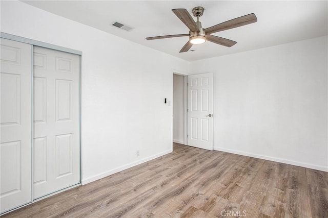 unfurnished bedroom featuring a closet, visible vents, baseboards, and wood finished floors