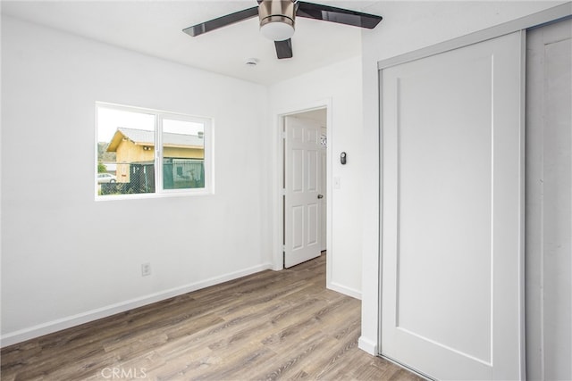 unfurnished bedroom with baseboards, a closet, light wood finished floors, and ceiling fan