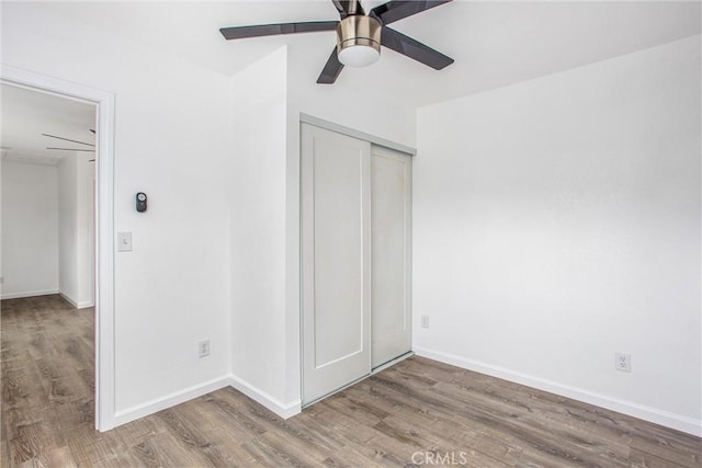 unfurnished bedroom with a closet, baseboards, and wood finished floors