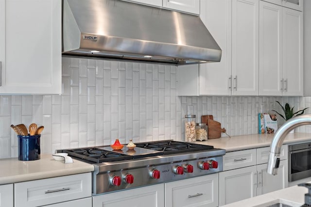 kitchen with under cabinet range hood, white cabinets, light countertops, and stainless steel gas stovetop