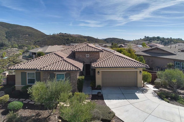 mediterranean / spanish house with a tile roof, concrete driveway, stucco siding, a garage, and a mountain view