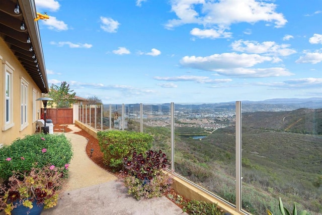 view of yard featuring a balcony, fence, and a mountain view