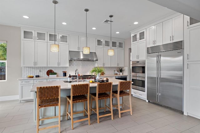 kitchen with visible vents, under cabinet range hood, tasteful backsplash, stainless steel appliances, and light countertops