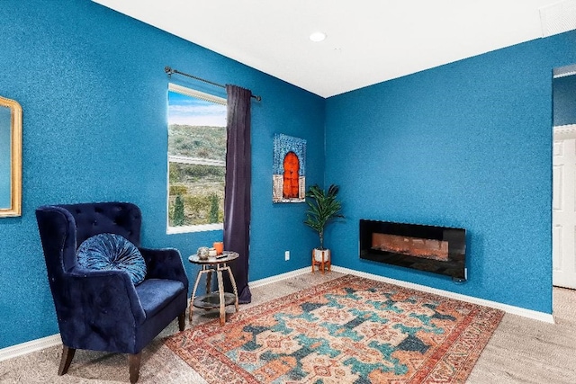 sitting room with carpet flooring, a glass covered fireplace, and baseboards