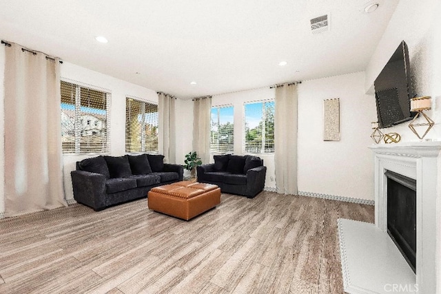 living area featuring light wood finished floors, a fireplace, and recessed lighting