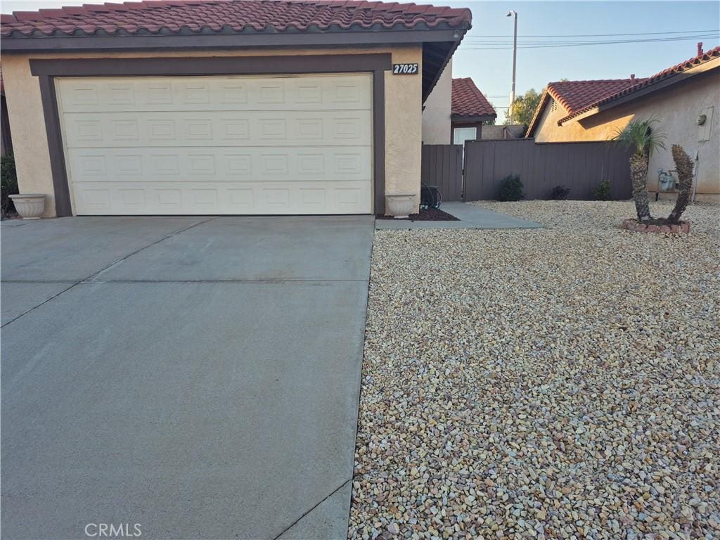 garage featuring driveway and fence