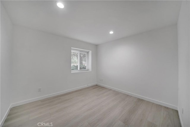 empty room with recessed lighting, light wood-style flooring, and baseboards