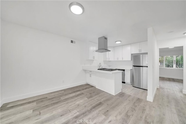 kitchen with white cabinetry, appliances with stainless steel finishes, a peninsula, island range hood, and light countertops