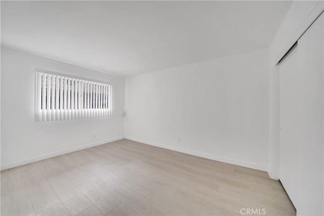 empty room with baseboards and light wood-style flooring