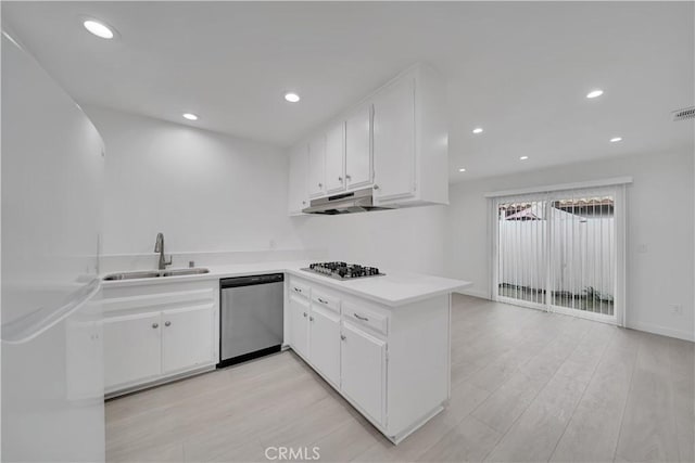 kitchen with a sink, under cabinet range hood, stainless steel appliances, white cabinets, and light countertops