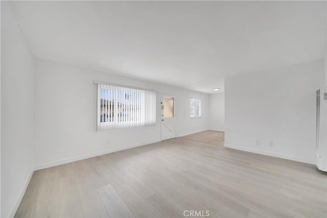 spare room featuring light wood-style floors and baseboards