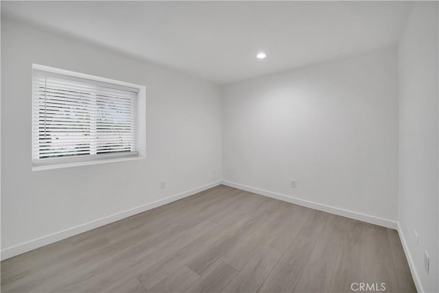 empty room with recessed lighting, wood finished floors, and baseboards