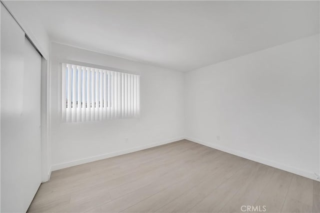 spare room featuring baseboards and light wood-style floors