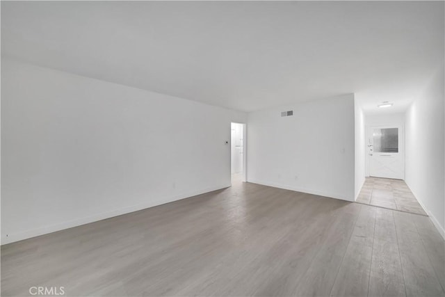 empty room featuring visible vents, baseboards, and wood finished floors