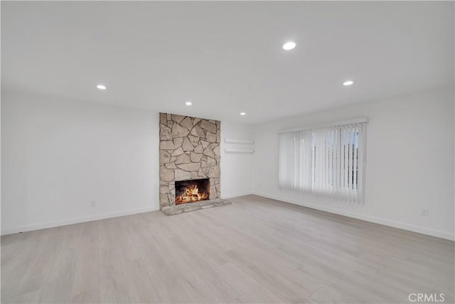 unfurnished living room with recessed lighting, a fireplace, baseboards, and wood finished floors