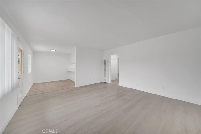 spare room with light wood-type flooring and baseboards