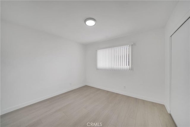 empty room featuring light wood-type flooring and baseboards