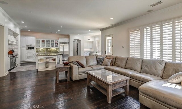living room with arched walkways, dark wood-style flooring, visible vents, recessed lighting, and crown molding