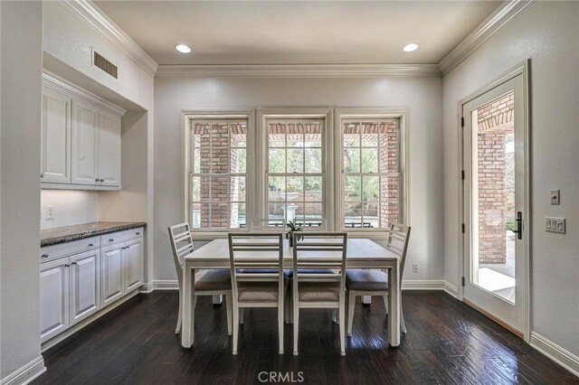 dining area featuring baseboards, visible vents, dark wood-type flooring, and crown molding