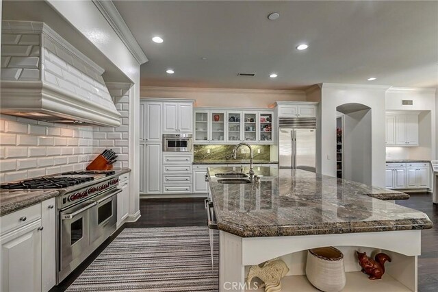 kitchen with crown molding, premium appliances, a sink, premium range hood, and white cabinets
