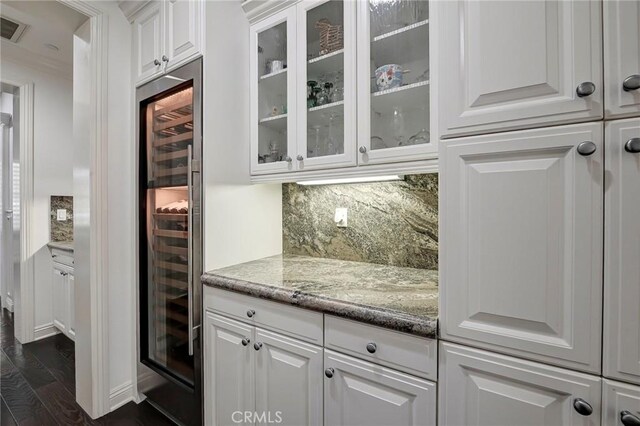 bar with backsplash, beverage cooler, visible vents, and dark wood-style flooring