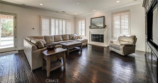 living room featuring recessed lighting, a glass covered fireplace, crown molding, and dark wood-style flooring