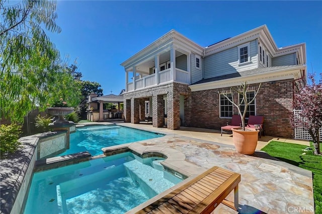 4 Andromeda Isle, Ladera Ranch, CA 92694 - back of property featuring a balcony, brick siding, a patio area, and a pool with connected hot tub