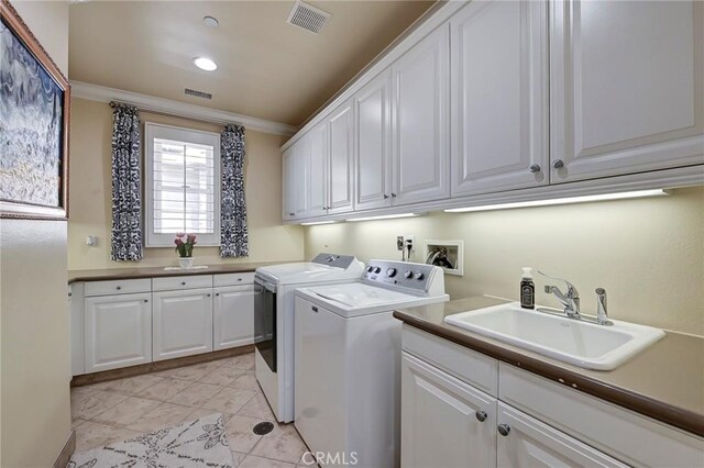 laundry area featuring visible vents, independent washer and dryer, a sink, and cabinet space