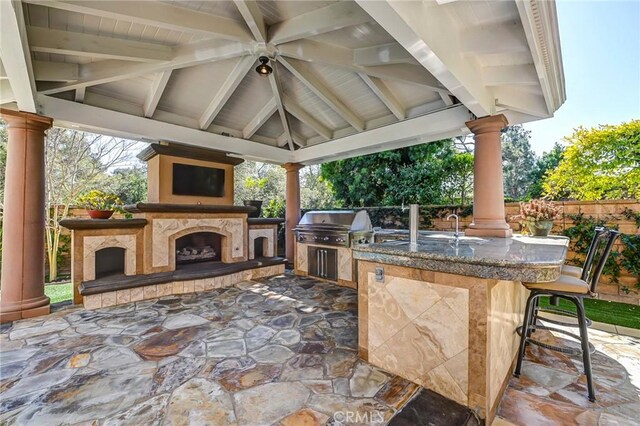 view of patio featuring an outdoor kitchen, grilling area, a gazebo, exterior fireplace, and outdoor wet bar
