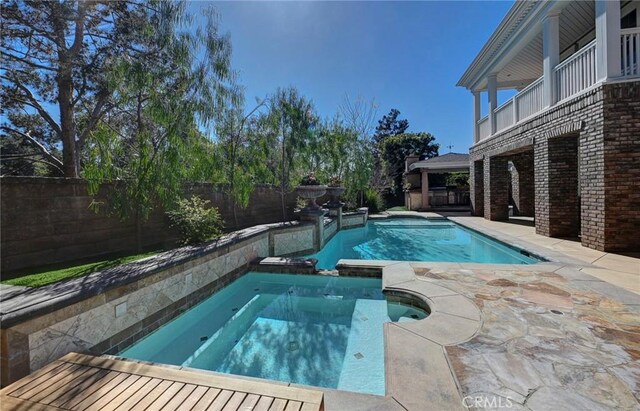 view of pool with a pool with connected hot tub, a patio, and a fenced backyard