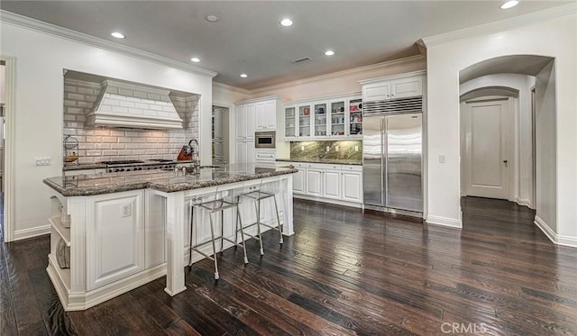4 Andromeda Isle, Ladera Ranch, CA 92694 - kitchen featuring stainless steel built in fridge, crown molding, premium range hood, dark wood finished floors, and decorative backsplash