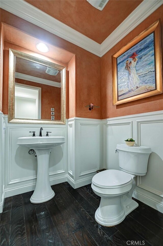 bathroom featuring wood finished floors, a decorative wall, toilet, and a wainscoted wall