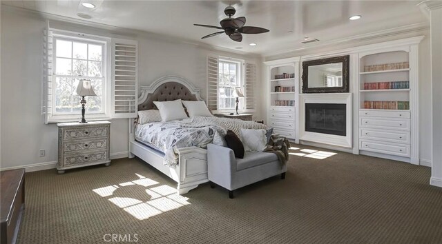 bedroom featuring recessed lighting, dark colored carpet, ornamental molding, baseboards, and a glass covered fireplace