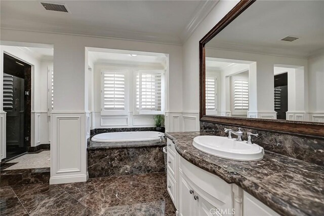 bathroom with crown molding, a decorative wall, a wainscoted wall, and visible vents