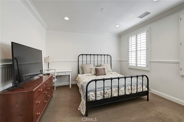 bedroom with dark carpet, visible vents, ornamental molding, and wainscoting