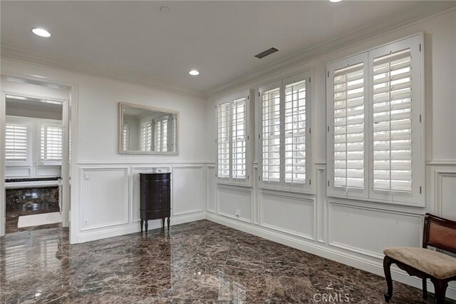 unfurnished living room featuring marble finish floor, a decorative wall, ornamental molding, and a wainscoted wall