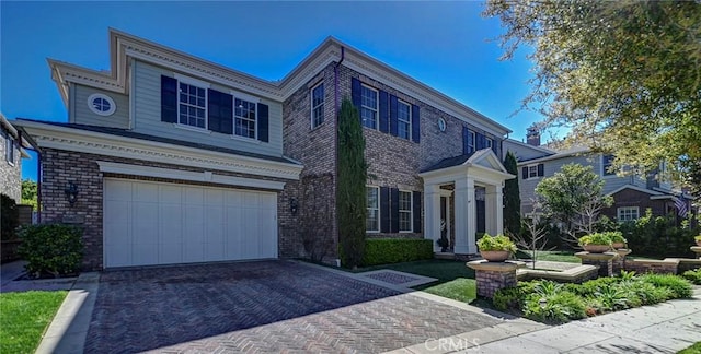 view of front of house with a garage, brick siding, and decorative driveway