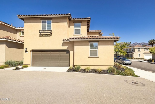 mediterranean / spanish-style home featuring stucco siding, concrete driveway, an attached garage, and a tiled roof