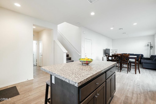 kitchen featuring a breakfast bar, light countertops, open floor plan, and light wood-type flooring