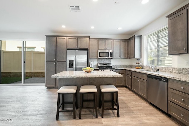kitchen with a breakfast bar area, visible vents, a sink, appliances with stainless steel finishes, and a center island