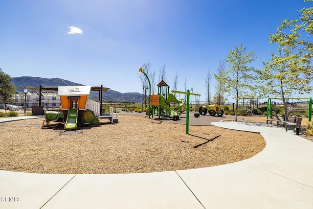 community play area featuring a mountain view and fence