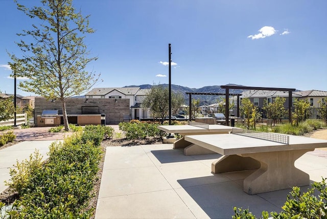 surrounding community with fence, exterior kitchen, a mountain view, a pergola, and a patio