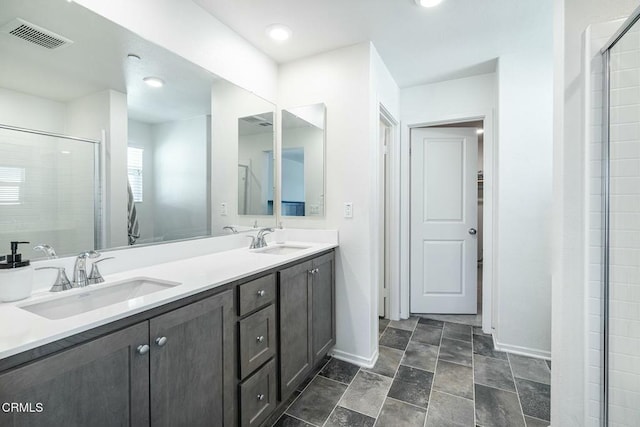 bathroom with a tile shower, visible vents, baseboards, and a sink