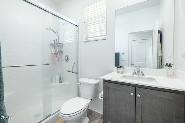 bathroom featuring vanity, toilet, wood finished floors, and a stall shower