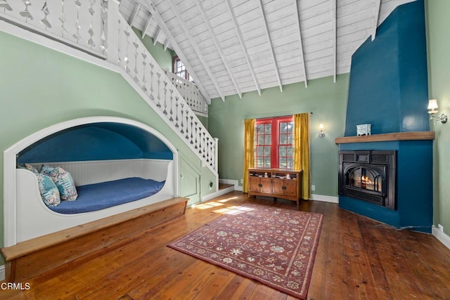 interior space featuring a fireplace, baseboards, wood-type flooring, and high vaulted ceiling