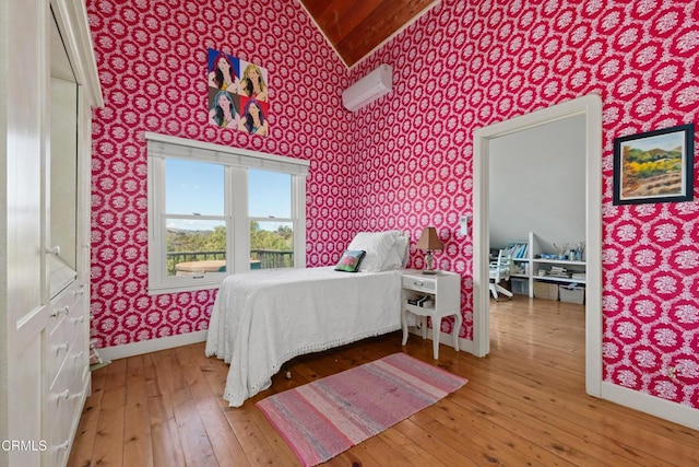 bedroom with wallpapered walls, lofted ceiling, baseboards, and hardwood / wood-style floors