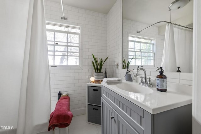 bathroom featuring tile patterned flooring, a healthy amount of sunlight, tile walls, and vanity