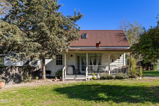 back of property featuring a porch, a lawn, and metal roof