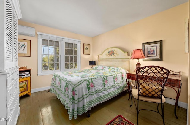 bedroom with baseboards, hardwood / wood-style floors, and a wall unit AC